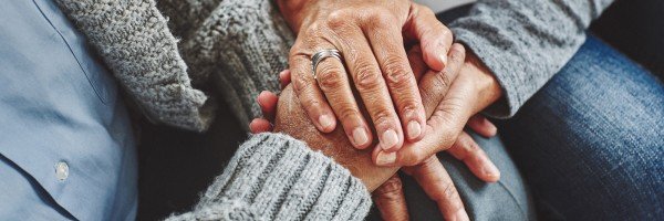 Two people holding hands to comfort each other