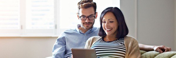 Couple sat on sofa looking at a tablet