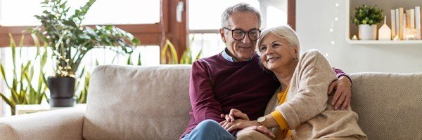 Older couple sat on sofa smiling