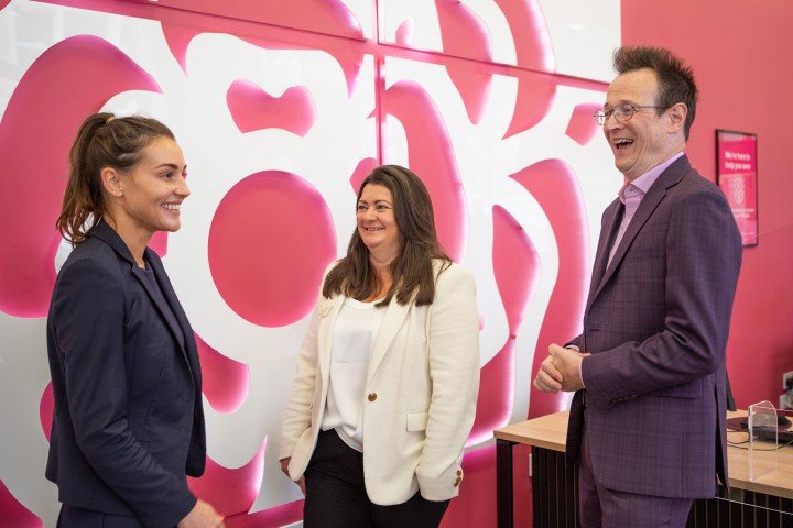 Marsden Building Society colleagues smiling and talking in front of a Marsden logo