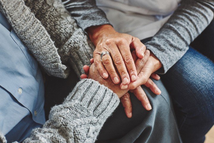 Two people holding hands to comfort each other