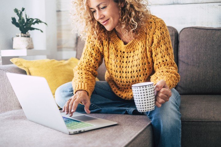 Mortgage Jargon: Woman sat on a sofa looking at a laptop 