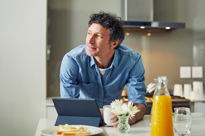 Man sits in his kitchen smiling after Mortgage Advice Bureau helped him to remortgage his property