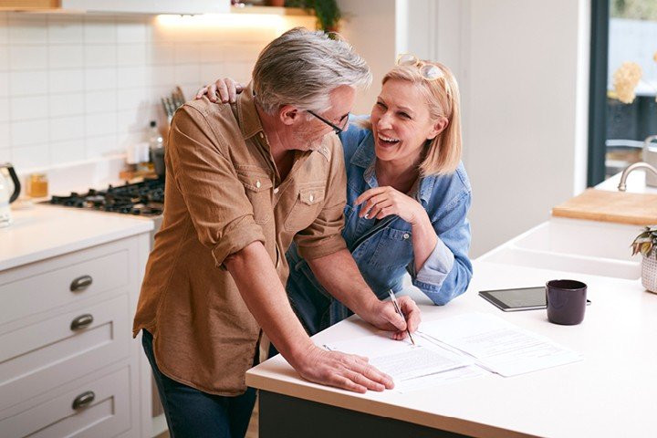 Couple chat happily in their kitchen after taking out a retirement mortgage with Mortgage Advice Bureau 